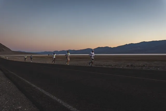 Runners on the road at Badwater Basin at dawn, mountains on the horizon
