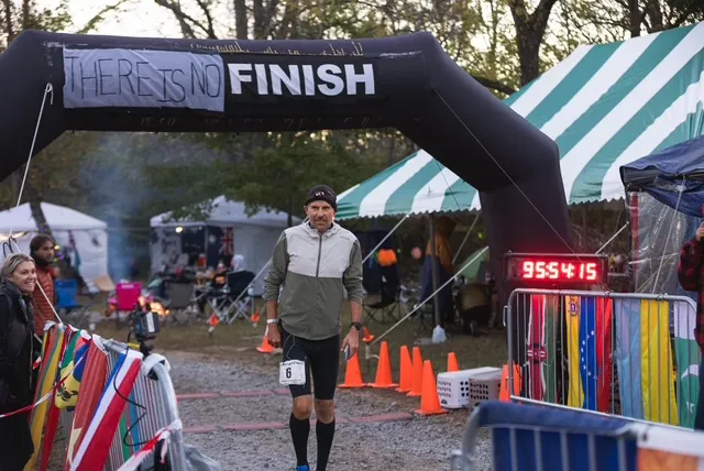 Harvey Lewis passing beneath the There Is No Finish arch at Big’s Backyard Ultra