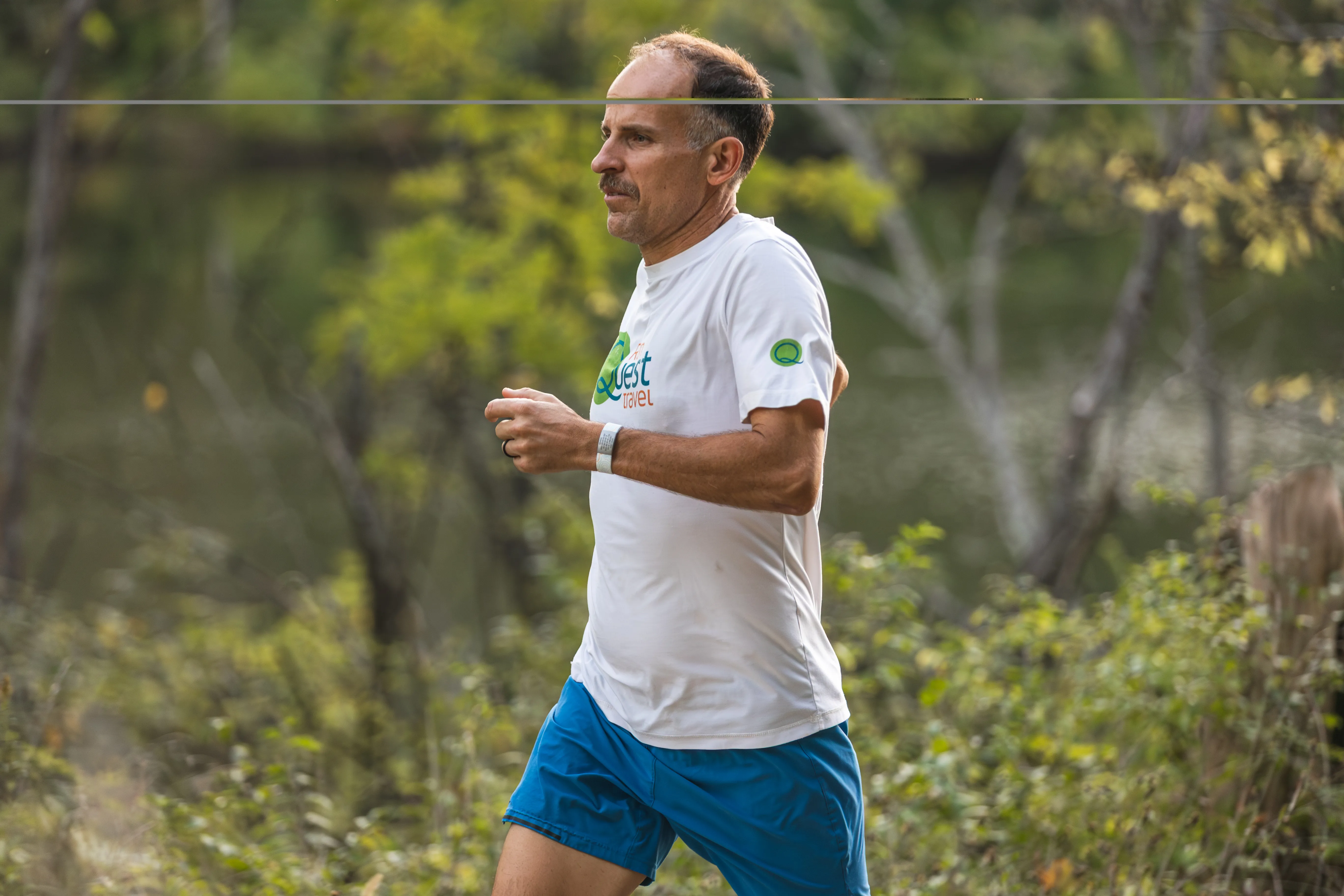 Harvey Lewis running a wooded trail beside a river